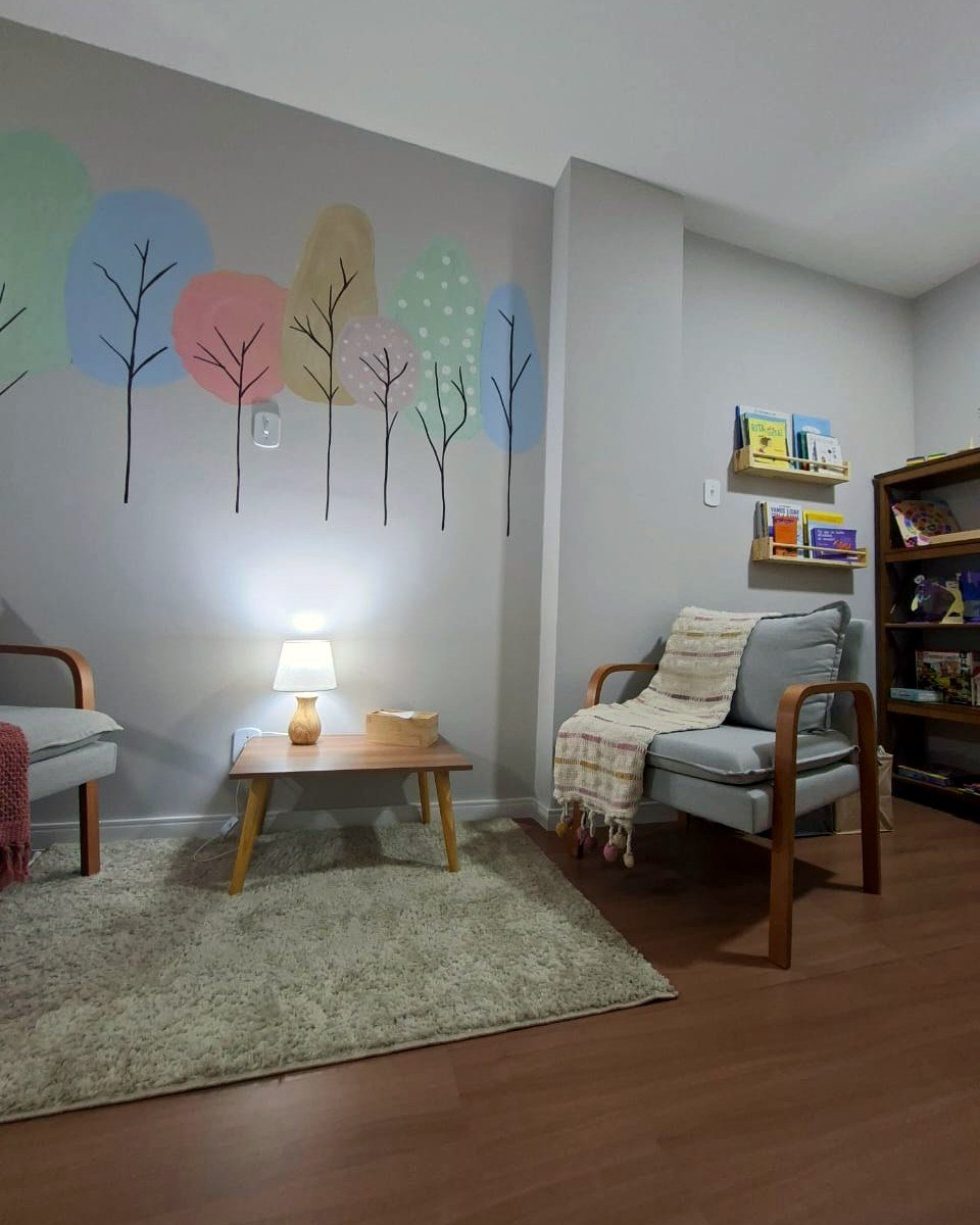 Ambiente acolhedor do consultório de Débora Peres, com poltronas confortáveis e cantinho de leitura infantil